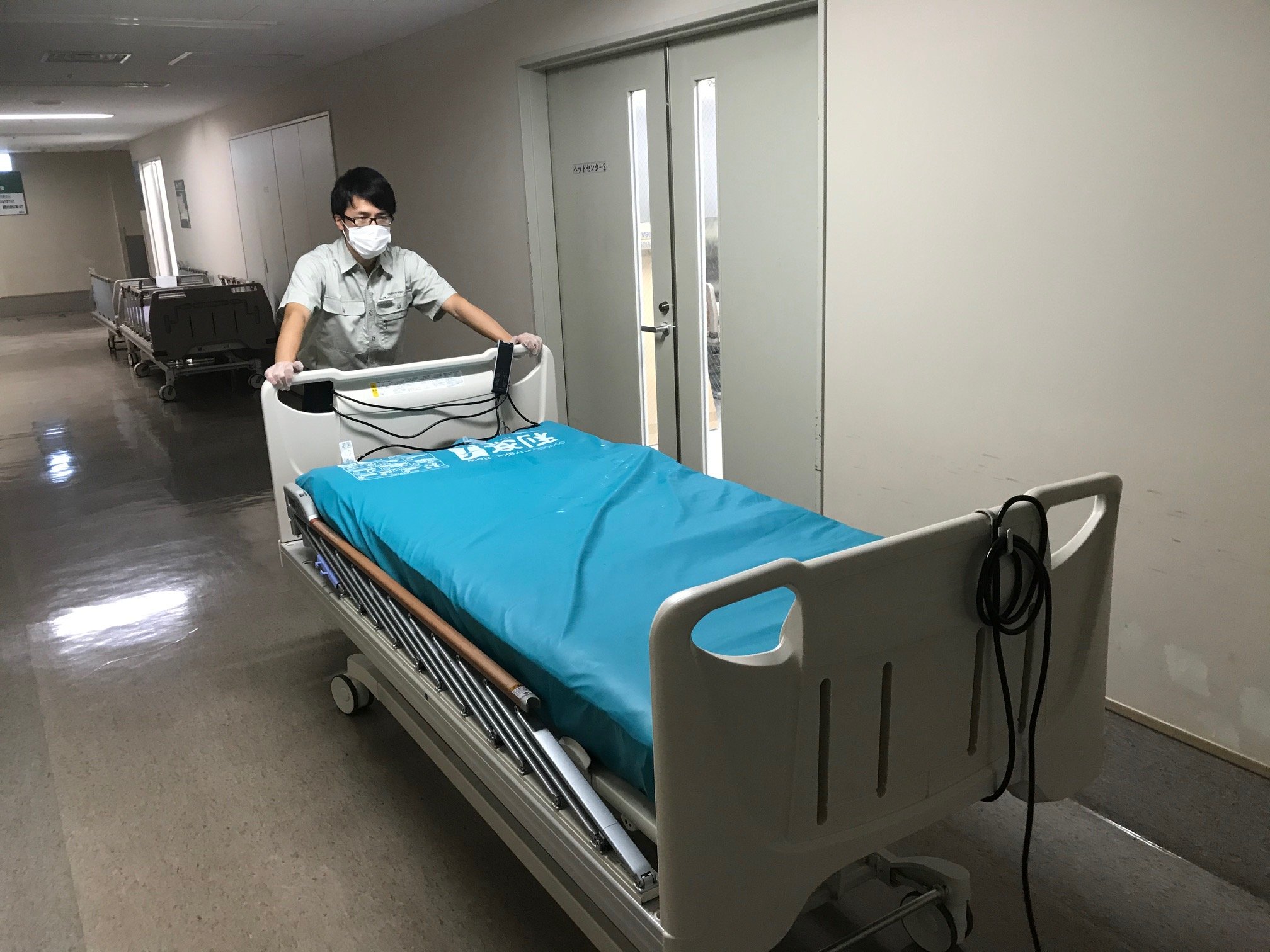 病棟からオーダーがあったベッドを搬送するパラテクノ株式会社スタッフ